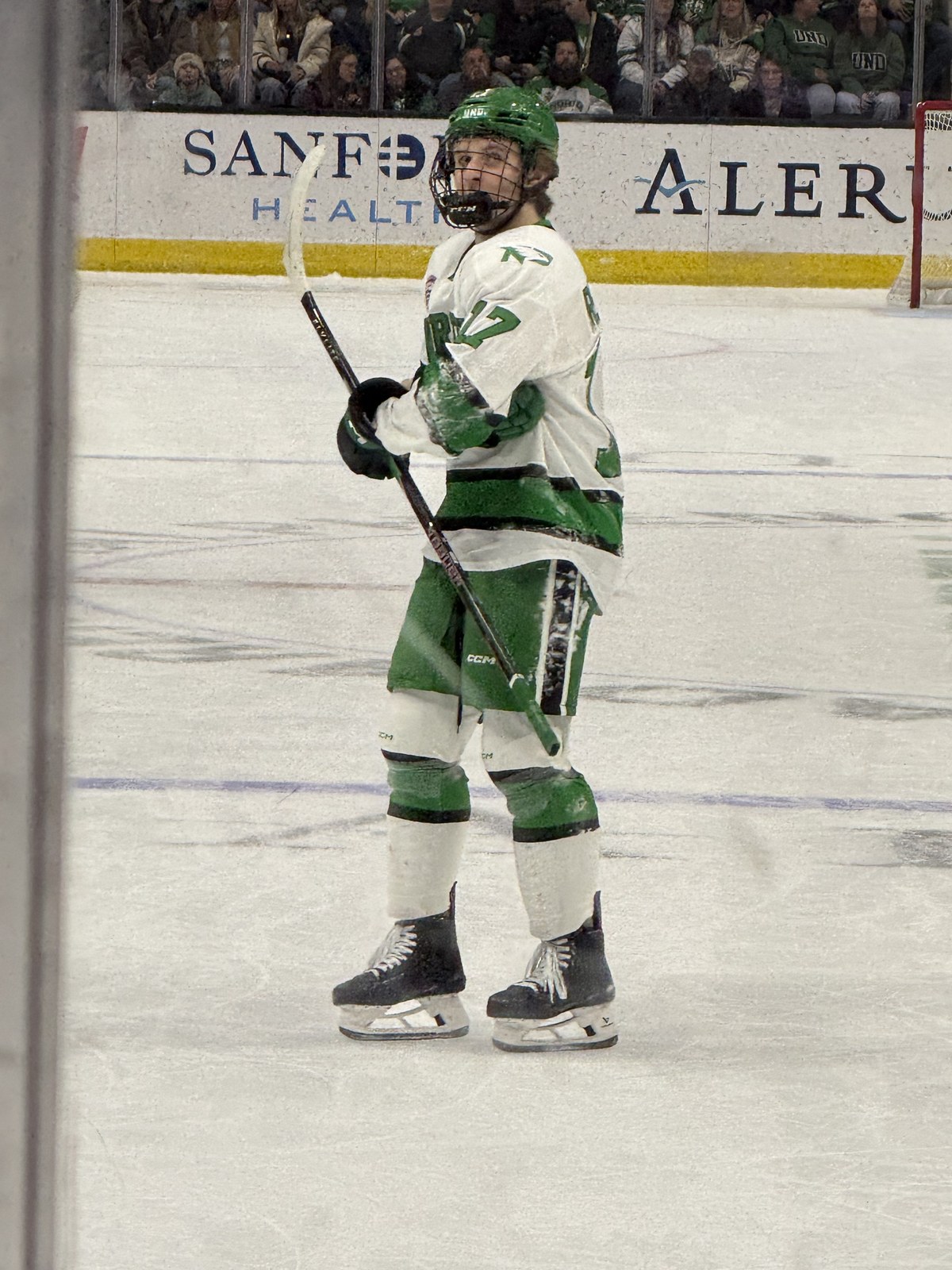 Cole Reschny in a North Dakota Fighting Hawks uniform, skating with his stick raised, during a February 2026 home game at Ralph Engelstad Arena.