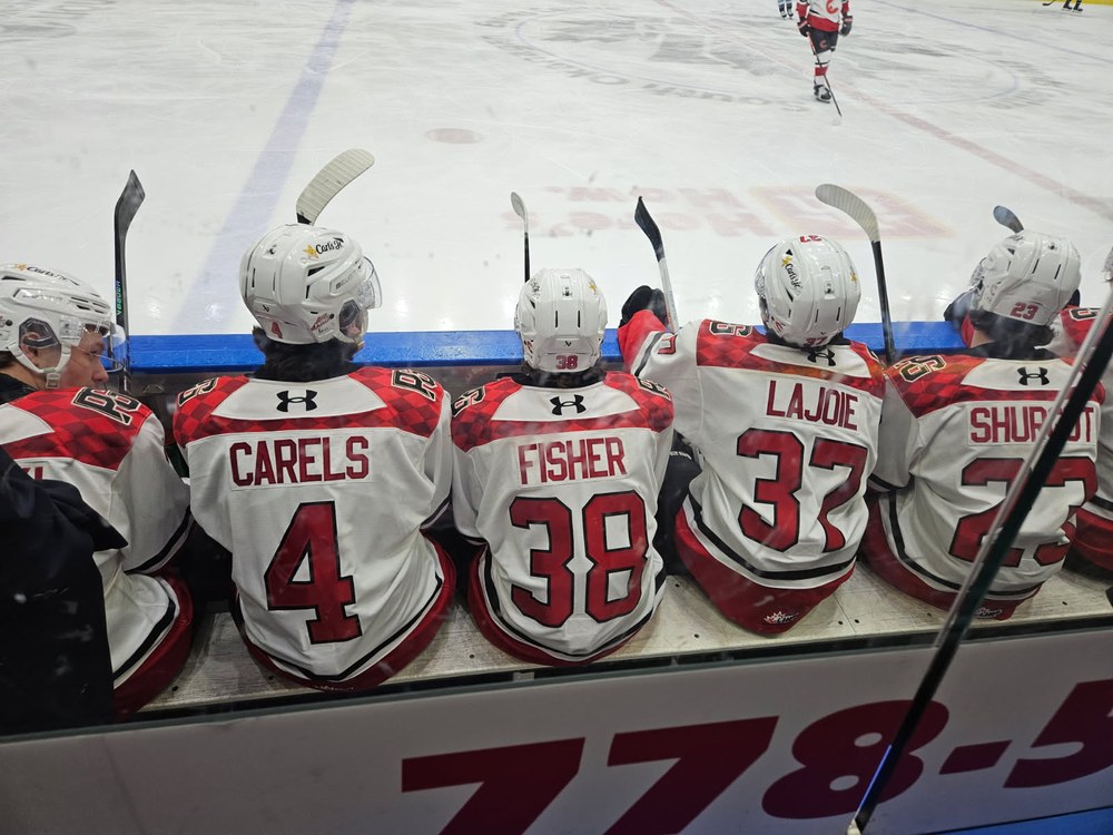Carson Carels, number 4, on the Prince George bench beside teammates Fisher, Lajoie and Shurgot, shot from the stands through the glass.