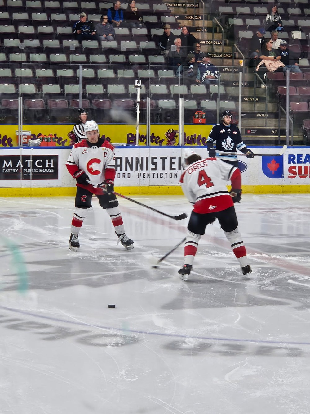 Carson Carels, number 4, facing a teammate on the ice during warm-ups in a mostly empty arena.